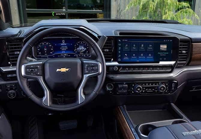 A modern car interior showing a Chevrolets dashboard. It features a digital gauge cluster and a large central touchscreen with various controls. The steering wheel has integrated buttons, and the console includes climate controls and storage space.