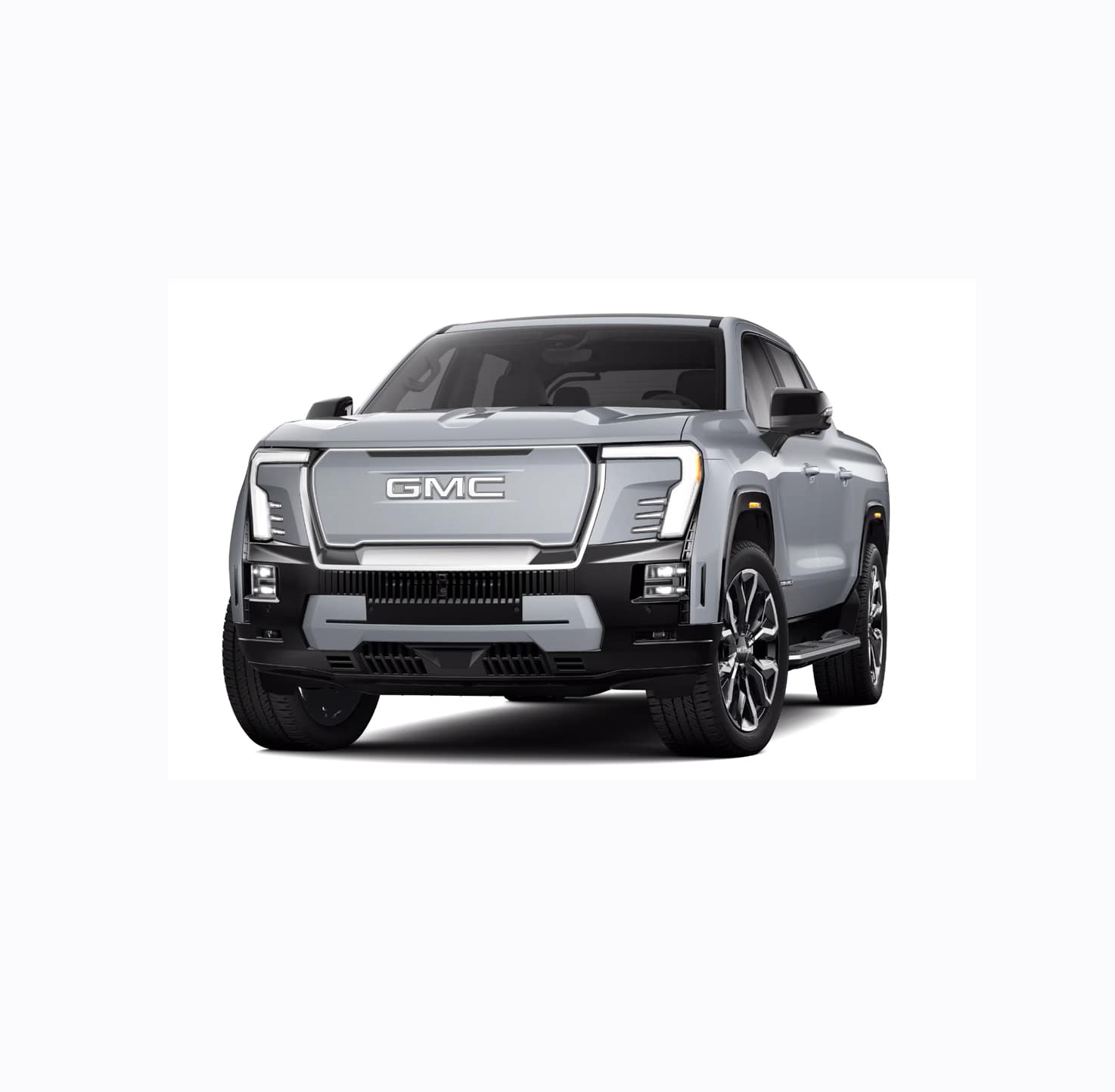 A silver GMC pickup truck is shown from the front, showcasing its bold grille, sleek headlights, and robust design. The truck has a modern appearance with black and chrome accents, emphasizing its sturdy build.