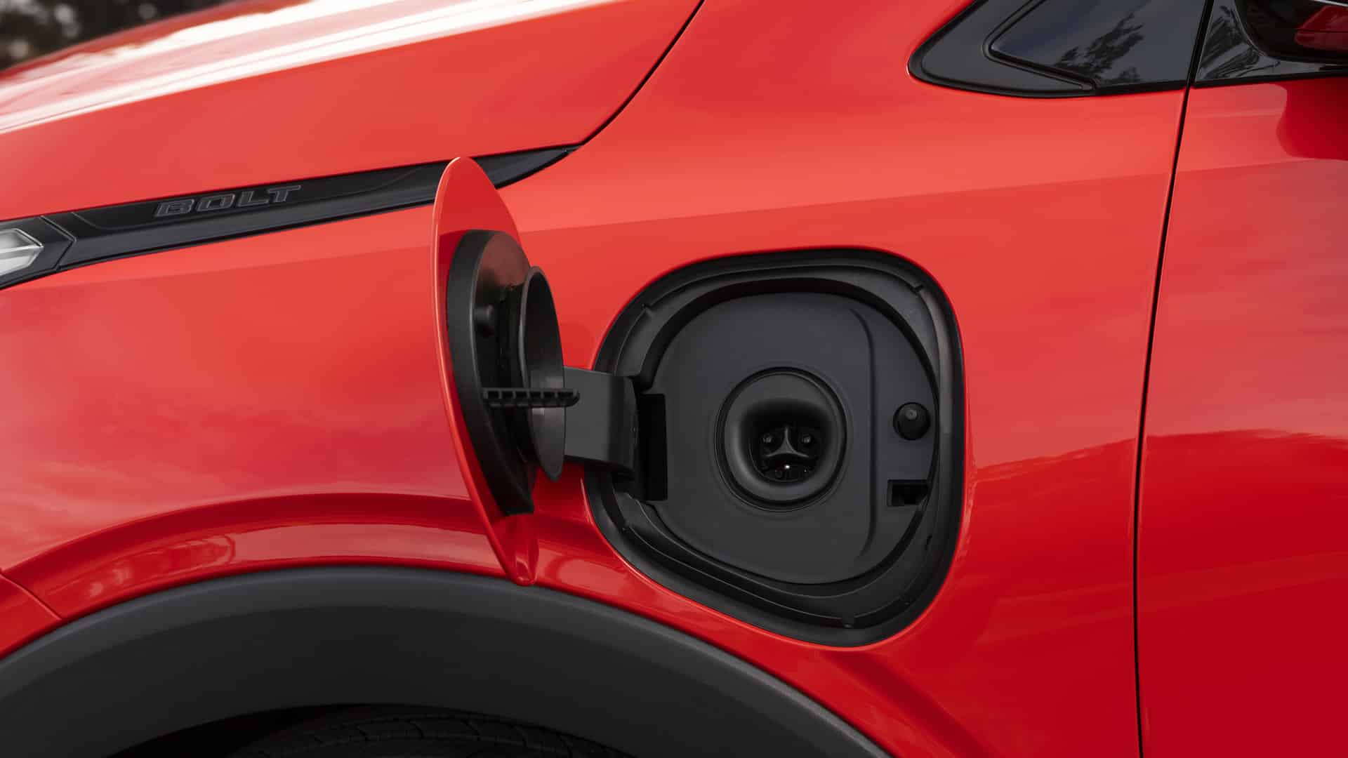 Red electric vehicle charging port with open cover, showing the connector area.