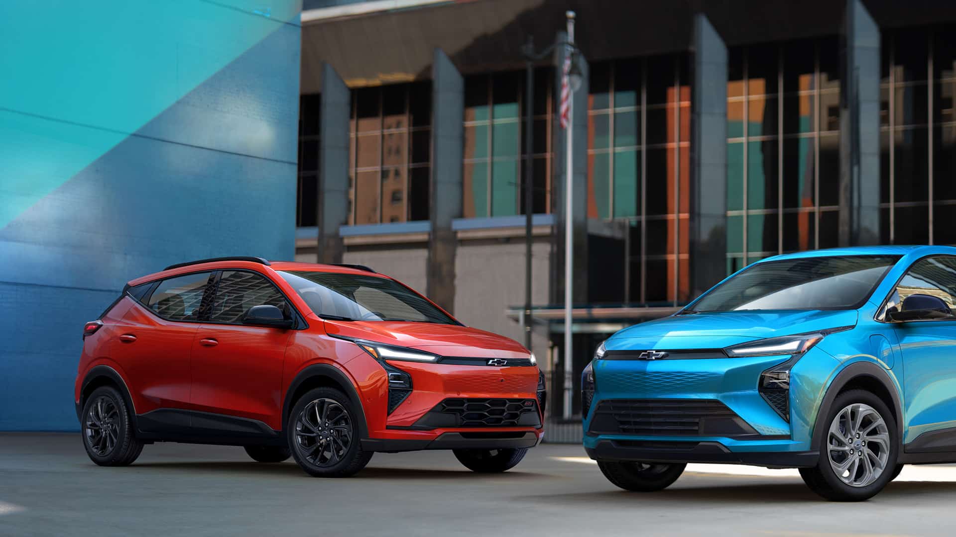 Red and blue Chevrolet electric SUVs parked in a modern urban setting.