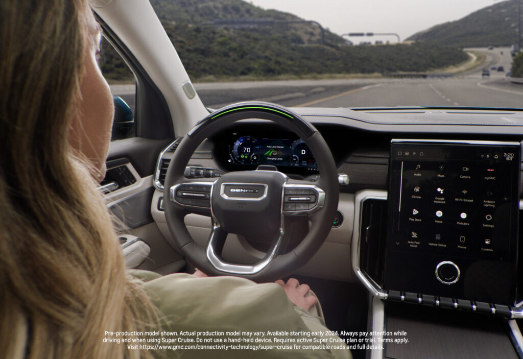 Driver's perspective in car with digital dashboard and touchscreen, traveling on a highway.