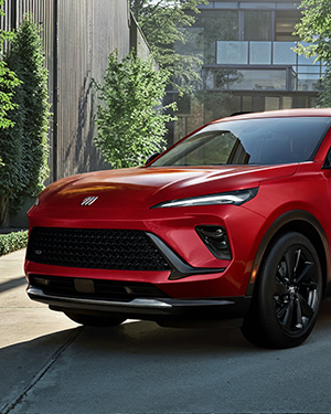 Red SUV parked on driveway, surrounded by greenery and modern building.